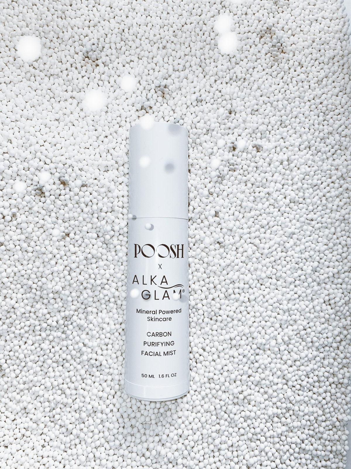 POOSH x ALKAGLAM Carbon Purifying Facial Mist bottle resting on a bed of white mineral pellets